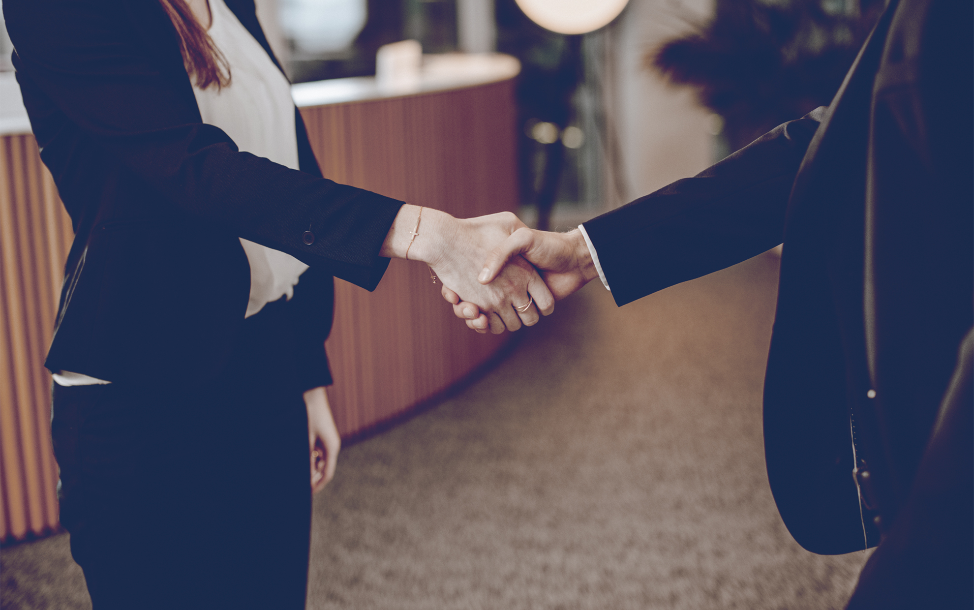 Two business people in formal attire shaking hands as a symbol of successful business partnership